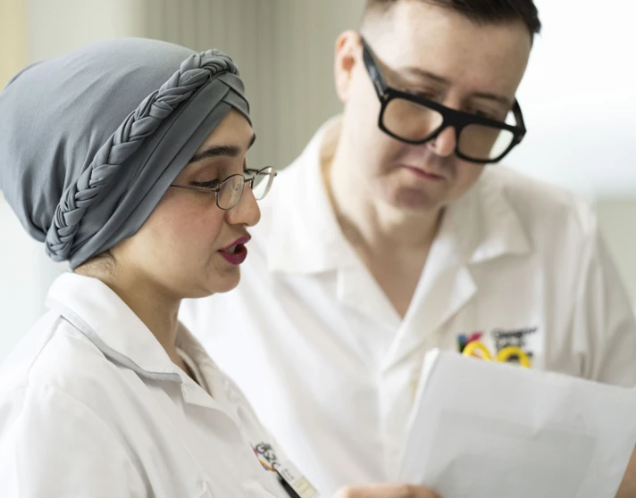 Close-up of two healthcare students reviewing patient notes in a practical classroom setting. Close-up of two healthcare students reviewing patient notes in a practical classroom setting.
